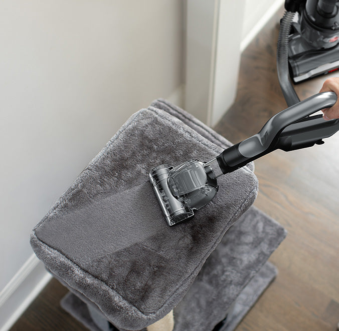 Hoover vacuum cleaner with turbo tool attachment efficiently cleaning a pet accessory.