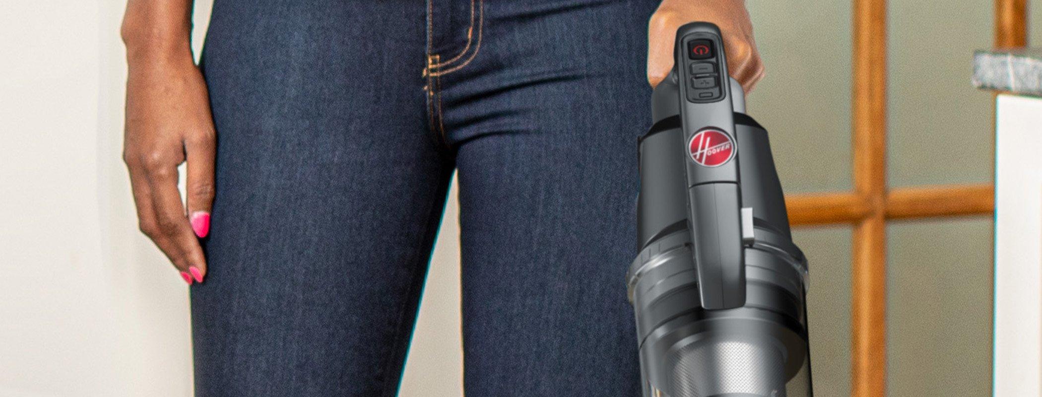 Close up view of the top of Hoover vacuum cleaner being held by a person, showcasing the ergonomic design and easy-to-use controls.