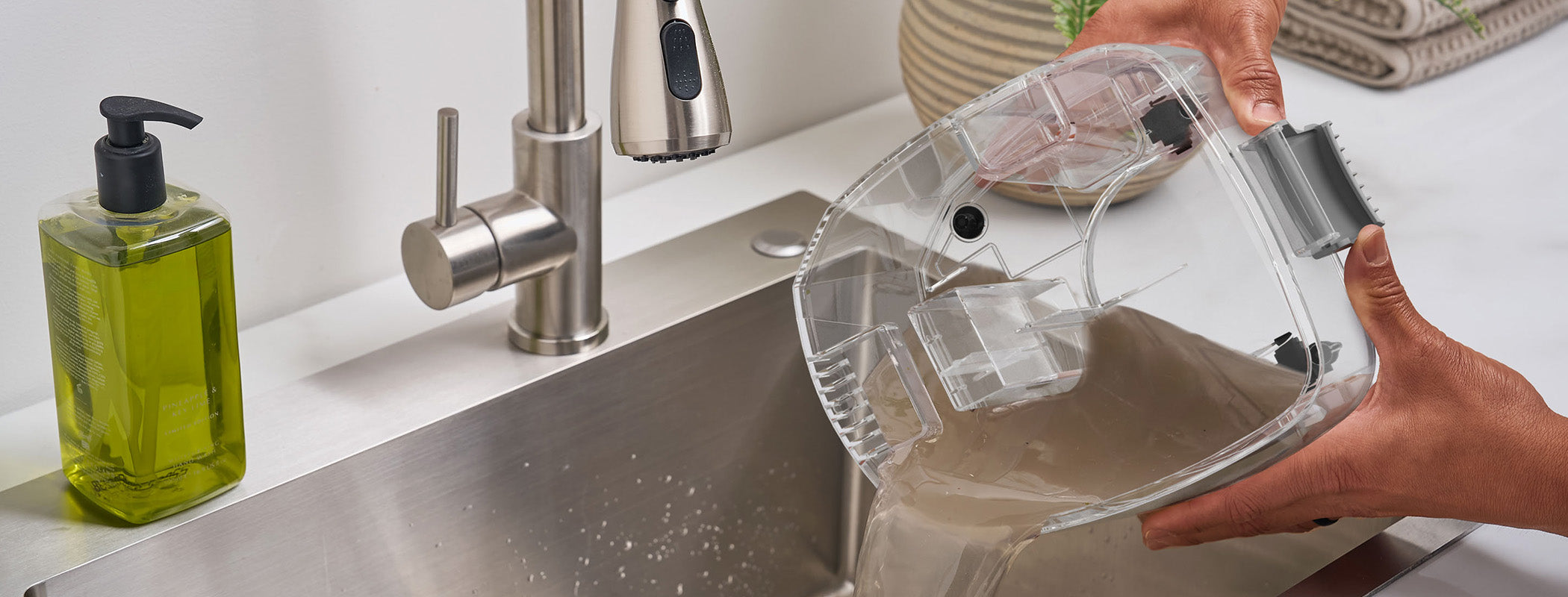 Person emptying dirty water tank from a Hoover carpet cleaner into a sink for easy cleaning.