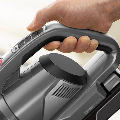Close up of a person holding the handle of a hoover vacuum cleaner, focusing on the ergonomic design and control buttons.