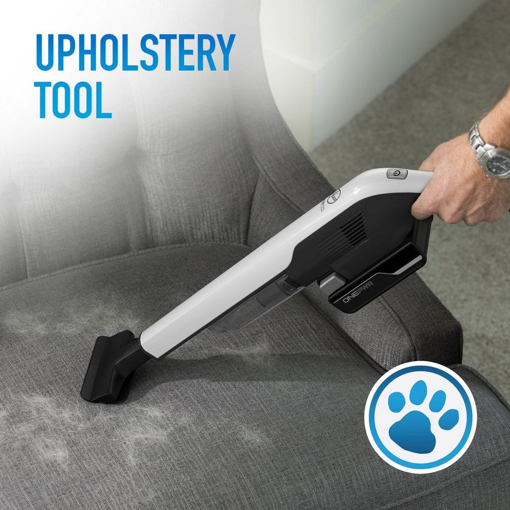 Handheld vacuum with an upholstery tool attachment cleaning pet hair from a gray chair, highlighting its pet-friendly cleaning capabilities.
