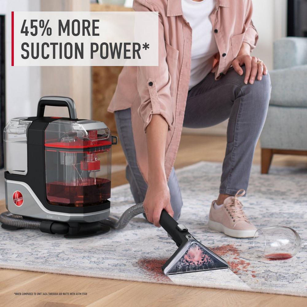 A person shown using their Hoover spot cleaner with 45% more suction power to remove a red wine stain from a carpet