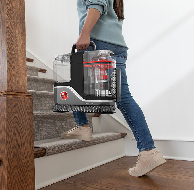 A person easily carrying the cleanslate xl spot cleaner up the stairs highlighting its lightweight design