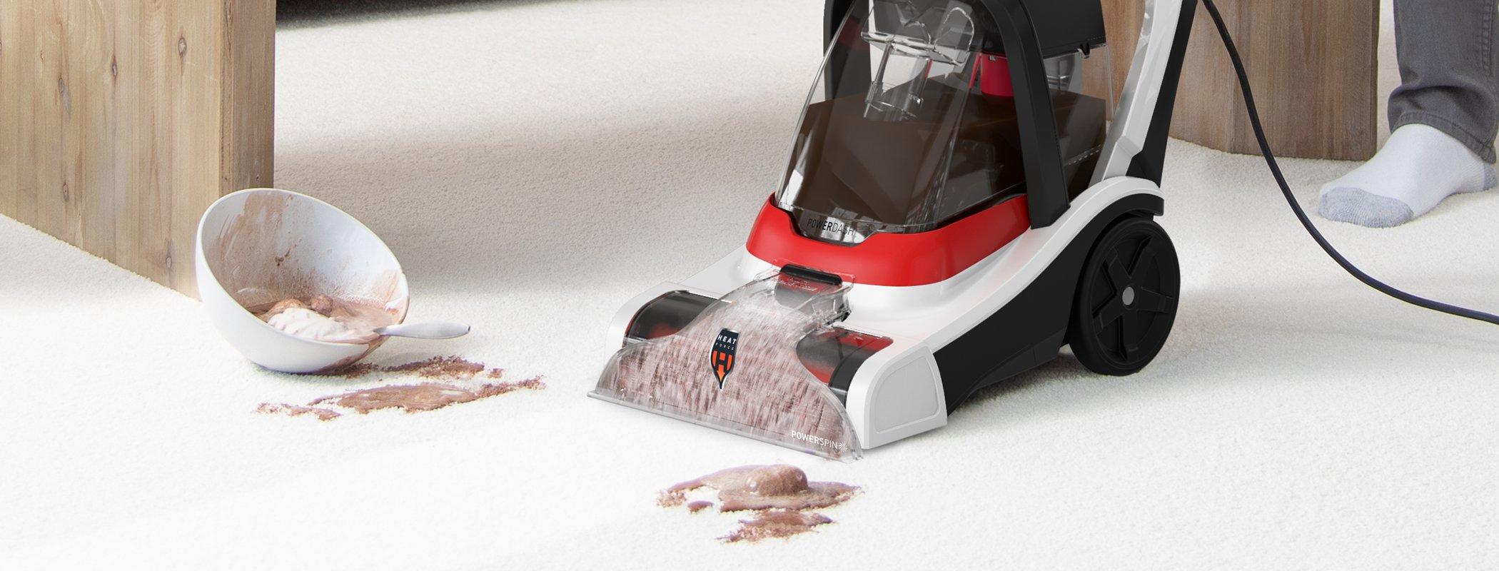 A Hoover carpet cleaner in action, cleaning up a spilled bowl of chocolate ice cream on a white carpet.
