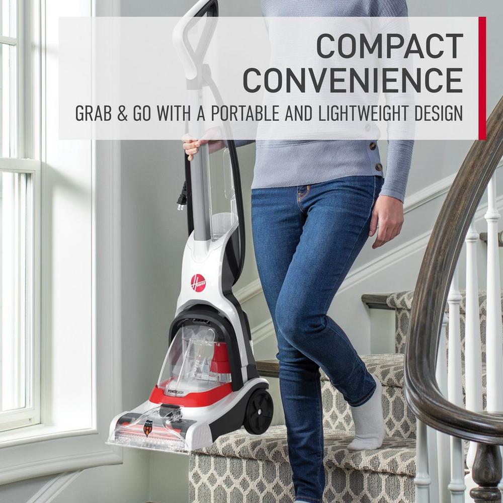 Person carrying a Hoover carpet cleaner with a compact and lightweight design while navigating stairs, showcasing its convenience for easy cleaning.