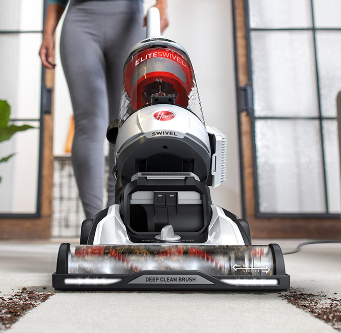 Hoover elite swivel vacuum cleaner with a deep clean brush, in use on a light colored carpet with visible dirt being cleaned.