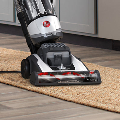 Hoover vacuum cleaner being used on a flat woven area rug showcasing its windtunnel technology and maxlife filtration system.