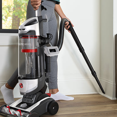 Hoover high performance swivel vacuum cleaner being used with the crevice tool attachment and hose to clean baseboards and corners.
