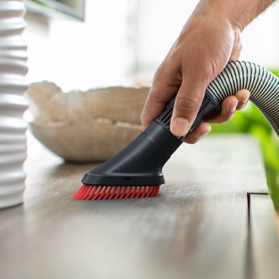 Close up of hand using a hoover pivoting dusting brush to dust a shelf, showcasing its cleaning versatility.
