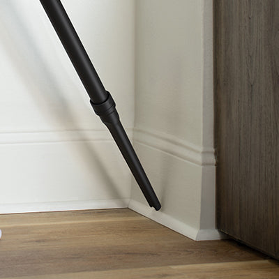Hoover crevice tool being used to clean baseboards, highlighting its ability to easily slide into tight spaces