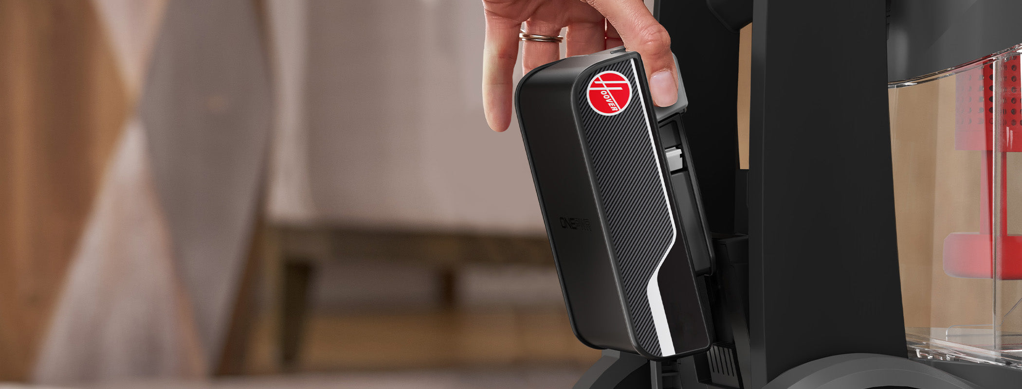 Close-up of a person inserting the ONEPWR battery into a Hoover carpet cleaner for cordless operation.