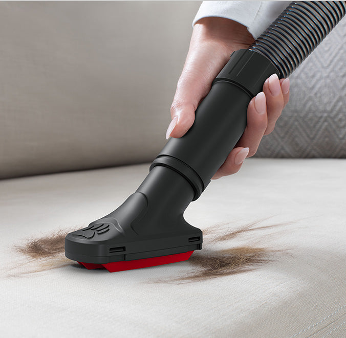 Close up of Hoover vacuum cleaner being used to remove pet hair from upholstery.