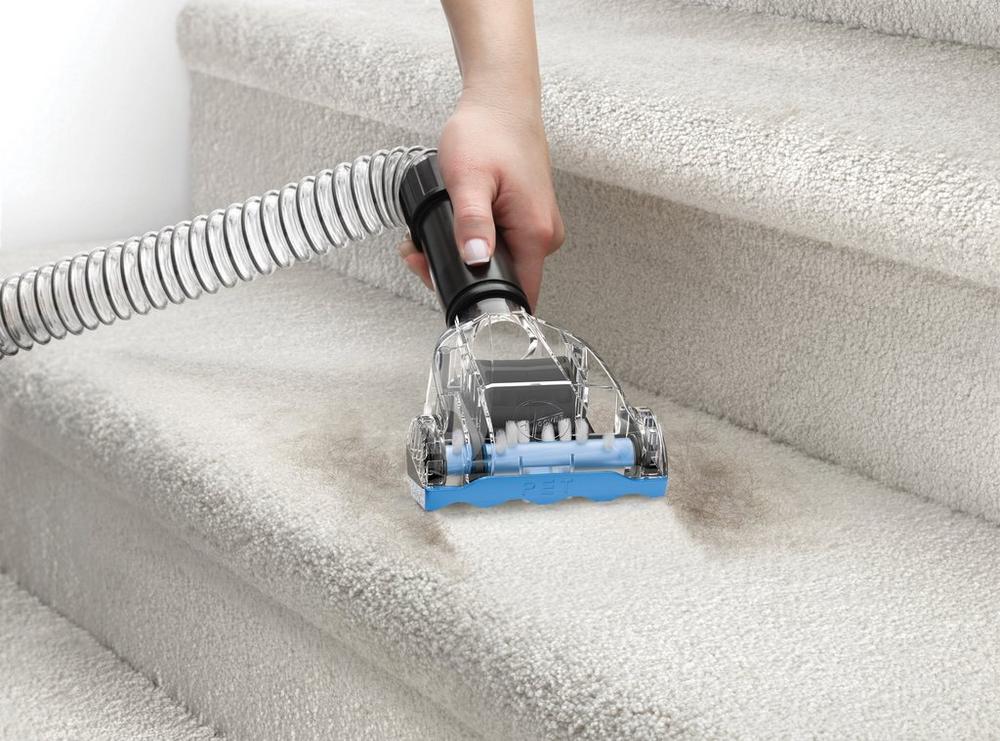 Person using a Hoover vacuum cleaner's turbo tool attachment to clean carpeted stairs