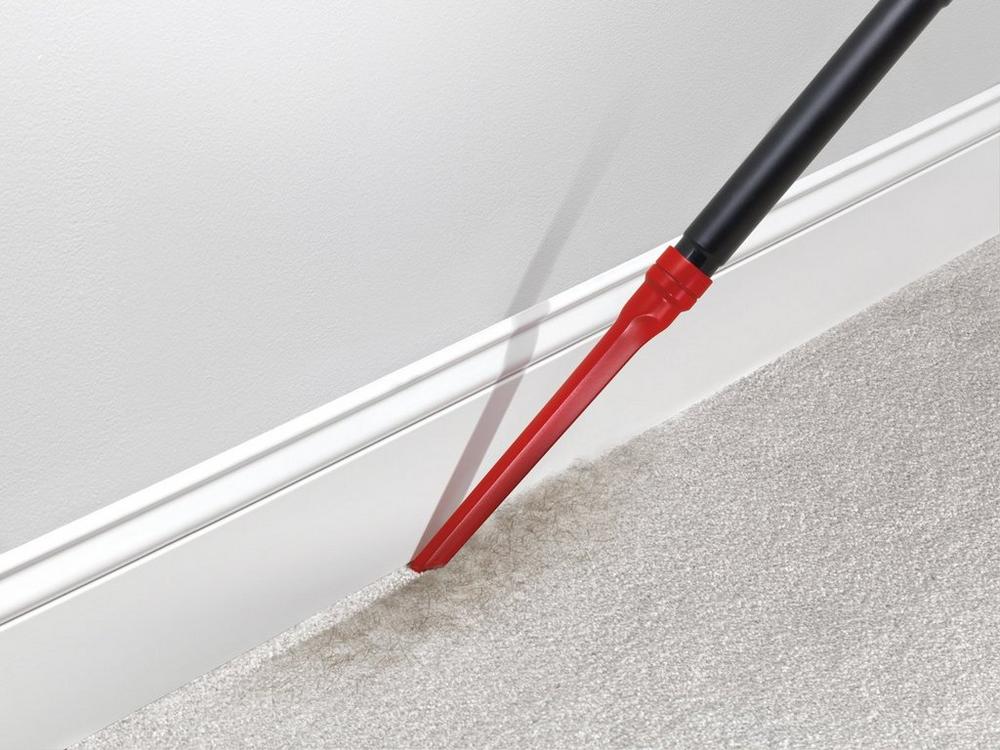 Hoover crevice tool being used to vacuum baseboards, highlighting its ability to clean hard-to-reach areas.