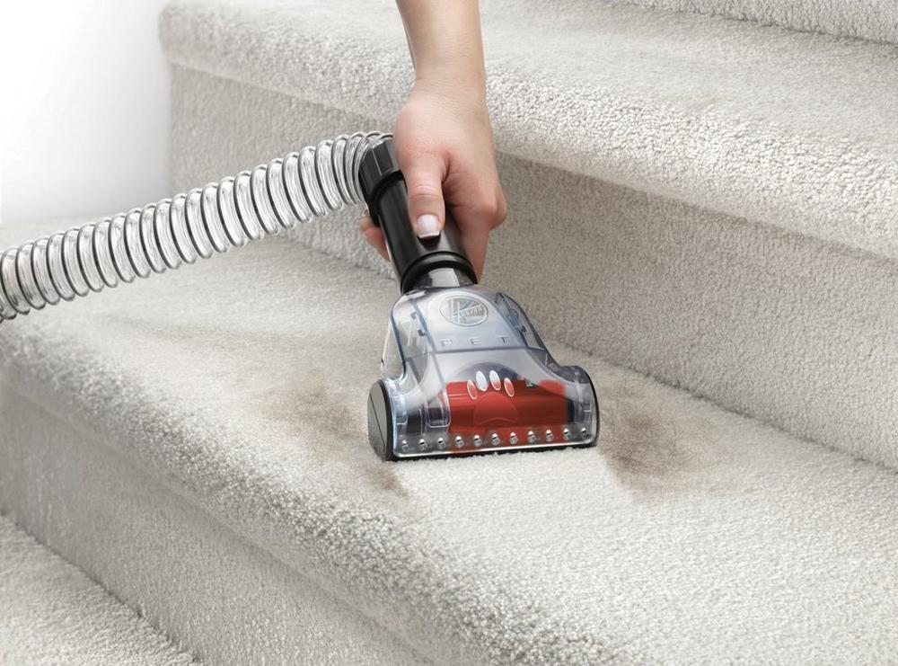Close up of hand using the pet turbo tool to vacuum pet hair from stairs