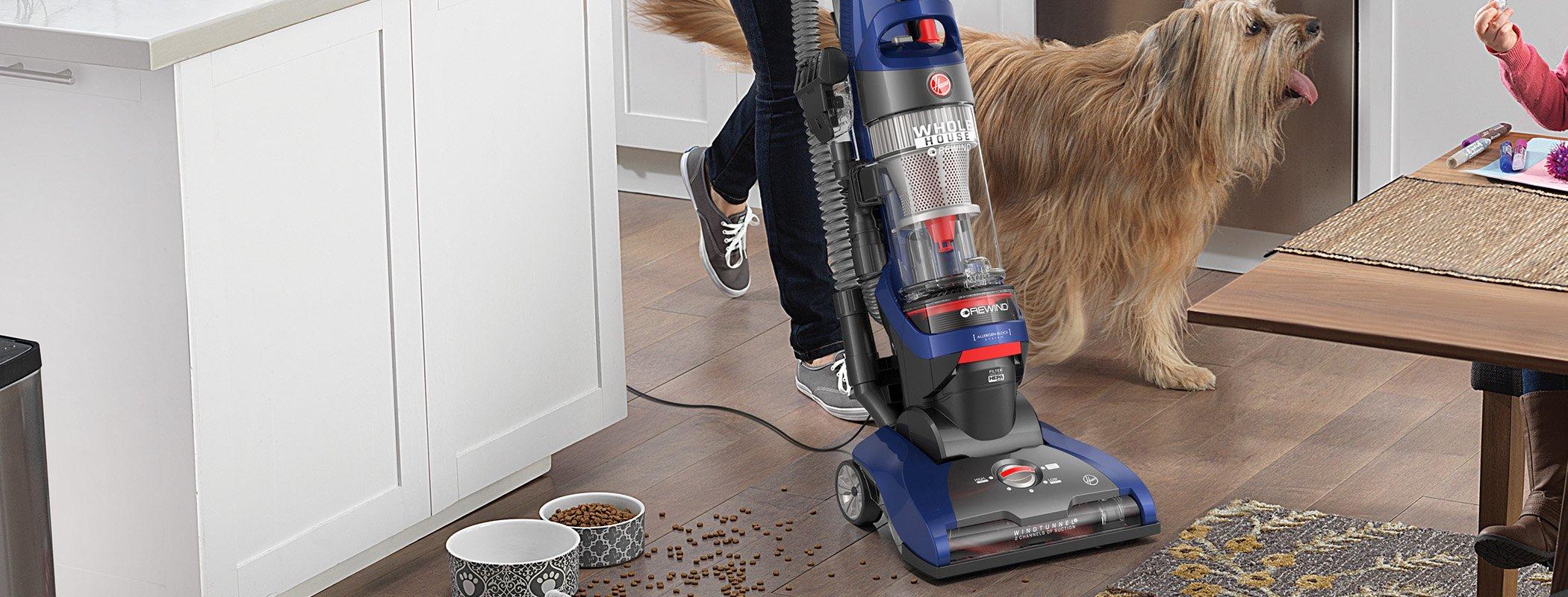 Close up of Hoover vacuum cleaner to vacuum scattered pet food from hard wood floors in the kitchen.