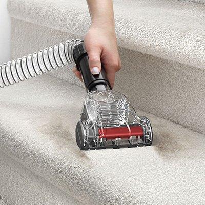 Close up of hand using the pet turbo tool to vacuum pet hair from stairs