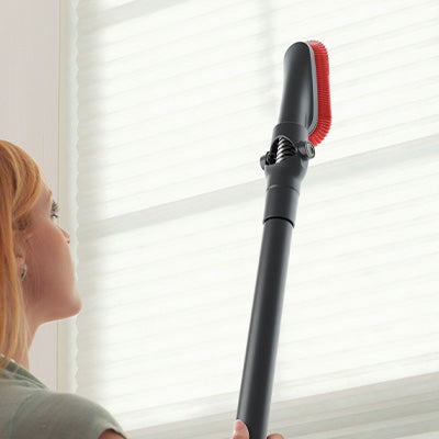 A person using a Hoover vacuum cleaner's extendable wand to clean window blinds demonstrating the tools versatility and ability to reach high places