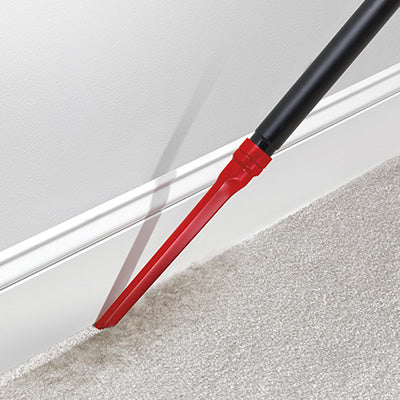 Close up of windtunnel vacuum cleaner's crevice tool cleaning along the baseboard on a carpeted floor.