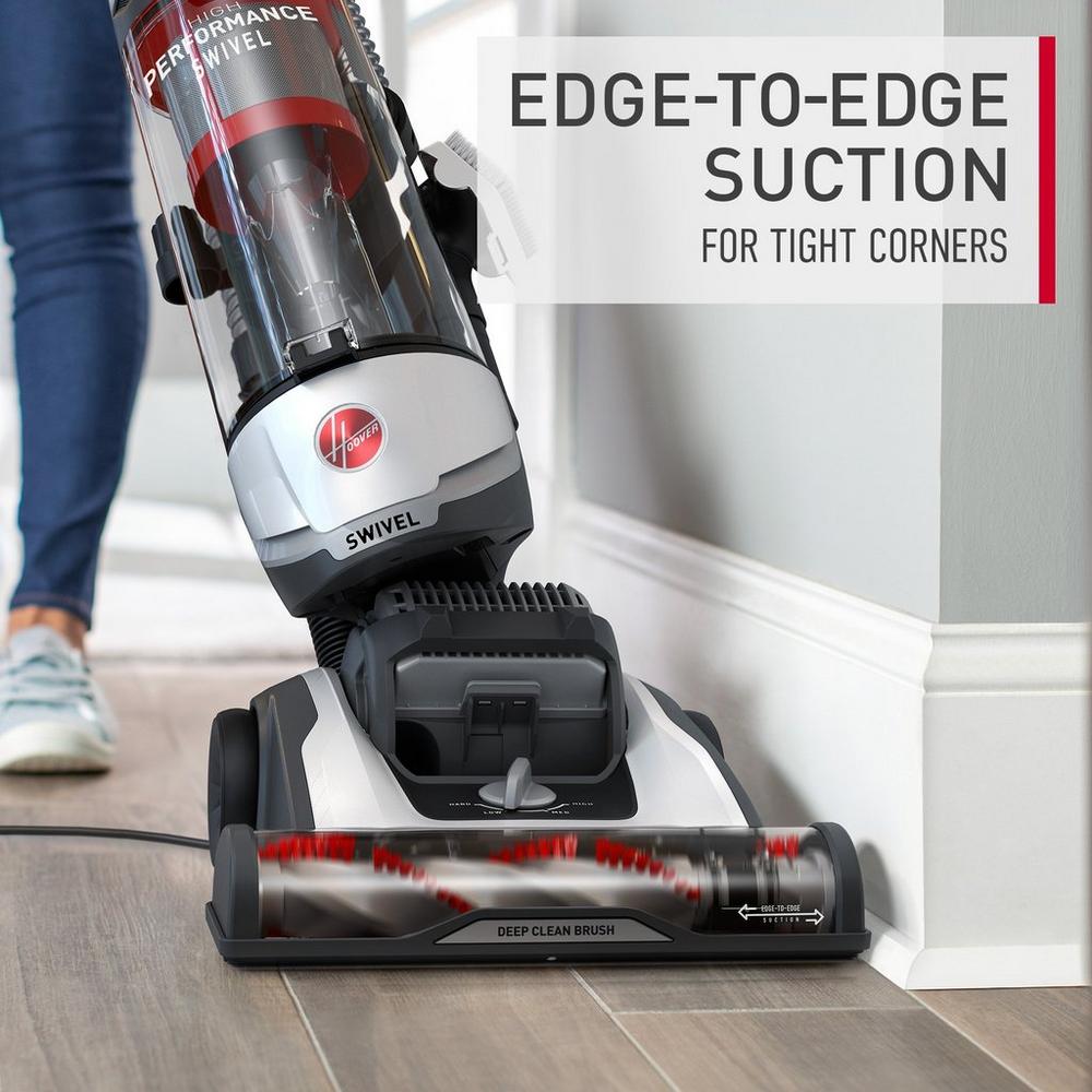 Hoover vacuum cleaner in action vacuuming along baseboards, showcasing its edge to edge suction, ideal for tight corners.