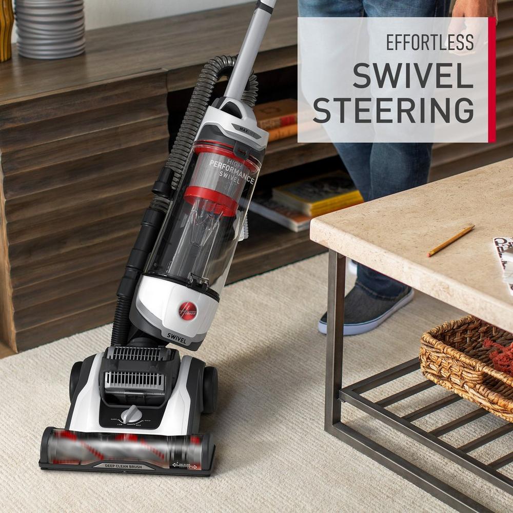 Hoover vacuum cleaner is shown maneuvering around a coffee table on a light colored carpet demonstrating its effortless swivel steering.