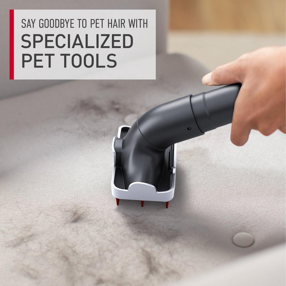 A hand using a specialized tool attachment to remove pet hair from a fabric surface. The image includes the text "say goodbye to pet hair with specialized pet tools," highlighting their effectiveness in cleaning pet hair