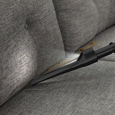 Hoover vacuum cleaner with LED crevice tool cleaning dirt and debris between couch cushions, highlighting precise cleaning in tight spaces