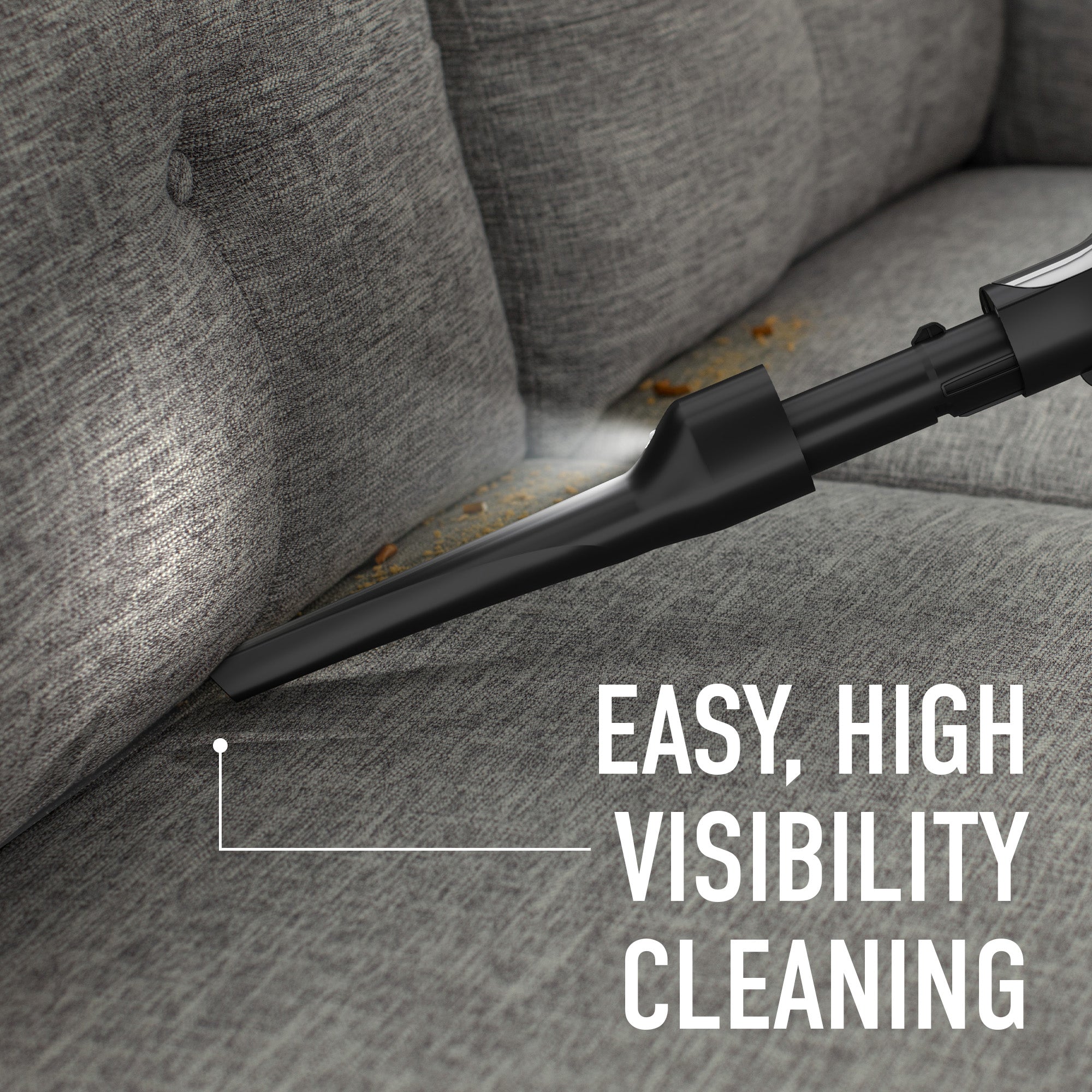 Close up of the LED crevice tool in action, vacuuming the tiny crumbs on a couch, that are clearly visible with the tool