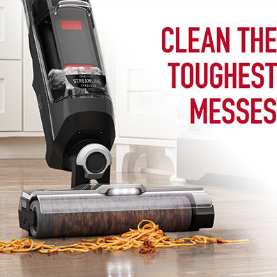 Hoover streamline cordless floor cleaner tackling a tough mess of spilled spaghetti on a hardwood floor, demonstrating powerful cleaning capability for challenging spills.  