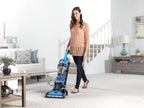 Person vacuuming a carpeted living room with a Hoover elite rewind, highlighting ease of use and effective carpet cleaning.