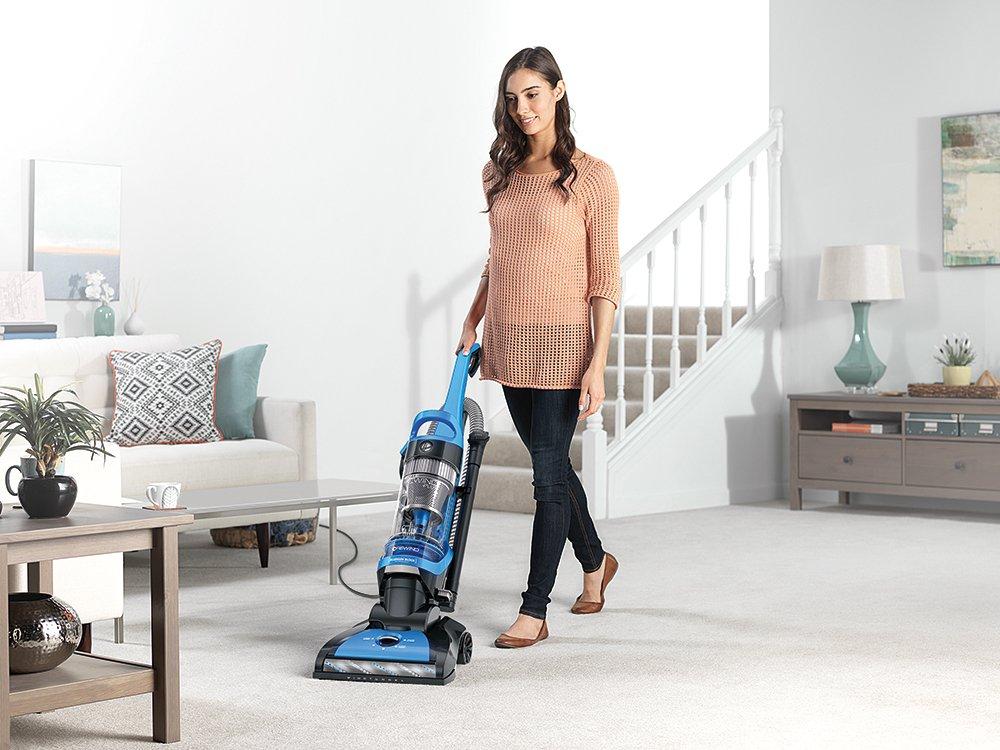 Person vacuuming a carpeted living room with a Hoover elite rewind, highlighting ease of use and effective carpet cleaning.