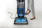 Close up of a person using the foot pedal on a Hoover vacuum cleaner to activate the automatic cord rewind feature, highlighting convenience and ease of use.