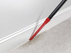 Hoover crevice tool being used to vacuum baseboards, highlighting its ability to clean hard-to-reach areas.
