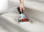 Close up of hand using the pet turbo tool to vacuum pet hair from stairs