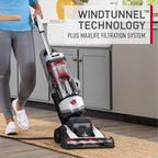 Hoover vacuum cleaner being used on a flat woven area rug showcasing its windtunnel technology and maxlife filtration system.  