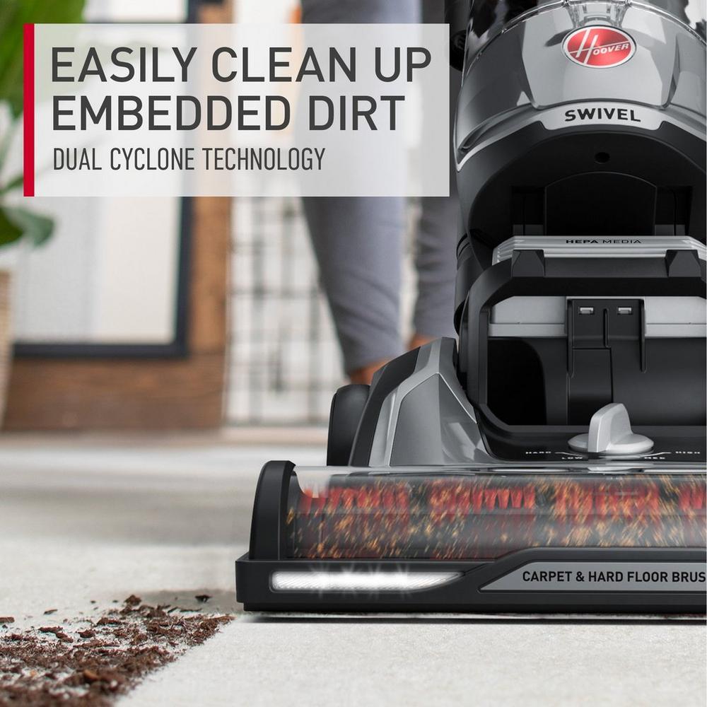 Close up of the Hoover vacuum cleaner's brush roll cleaning embedded dirt from a carpet, highlighting the vacuum's powerful cleaning capabilities and advanced technology.