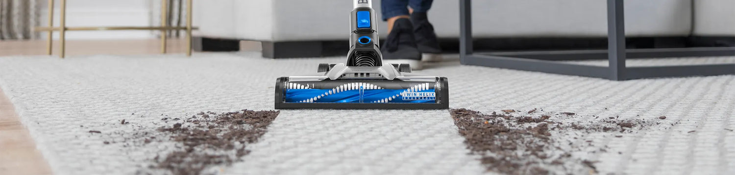 Hoover blade vacuuming dirt and debris off of grey carpet  